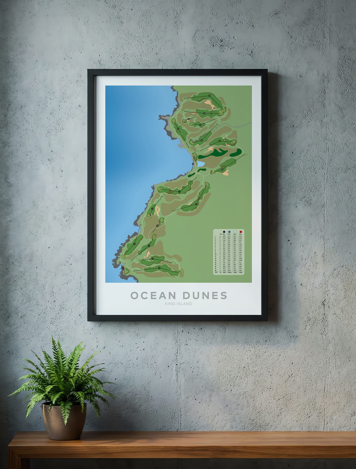 A framed golf course map poster titled 'OCEAN DUNES' hangs on a textured gray concrete wall above a wooden shelf with a potted fern. The poster shows a stylized green and blue map with a small course legend.-australia-golf-art