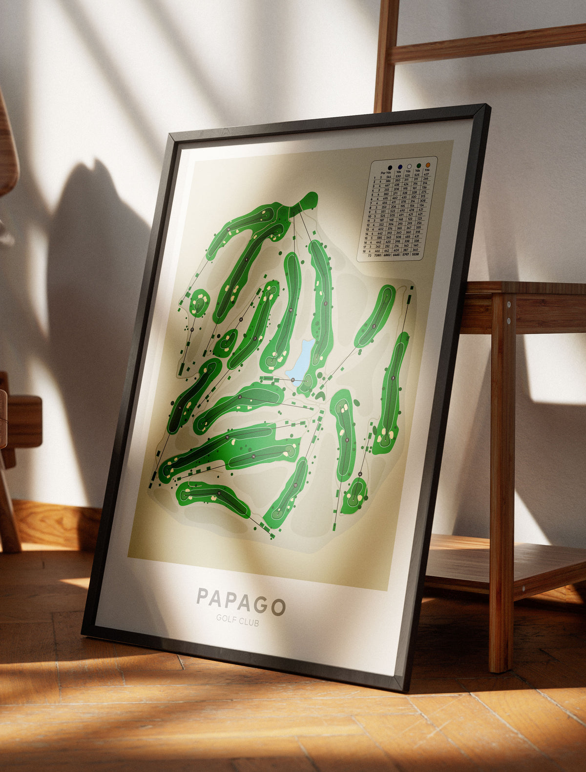 Black framed art print featuring a green abstract map design 'PAPAGO', leaning against a wall on a wooden floor in a sunlit room.