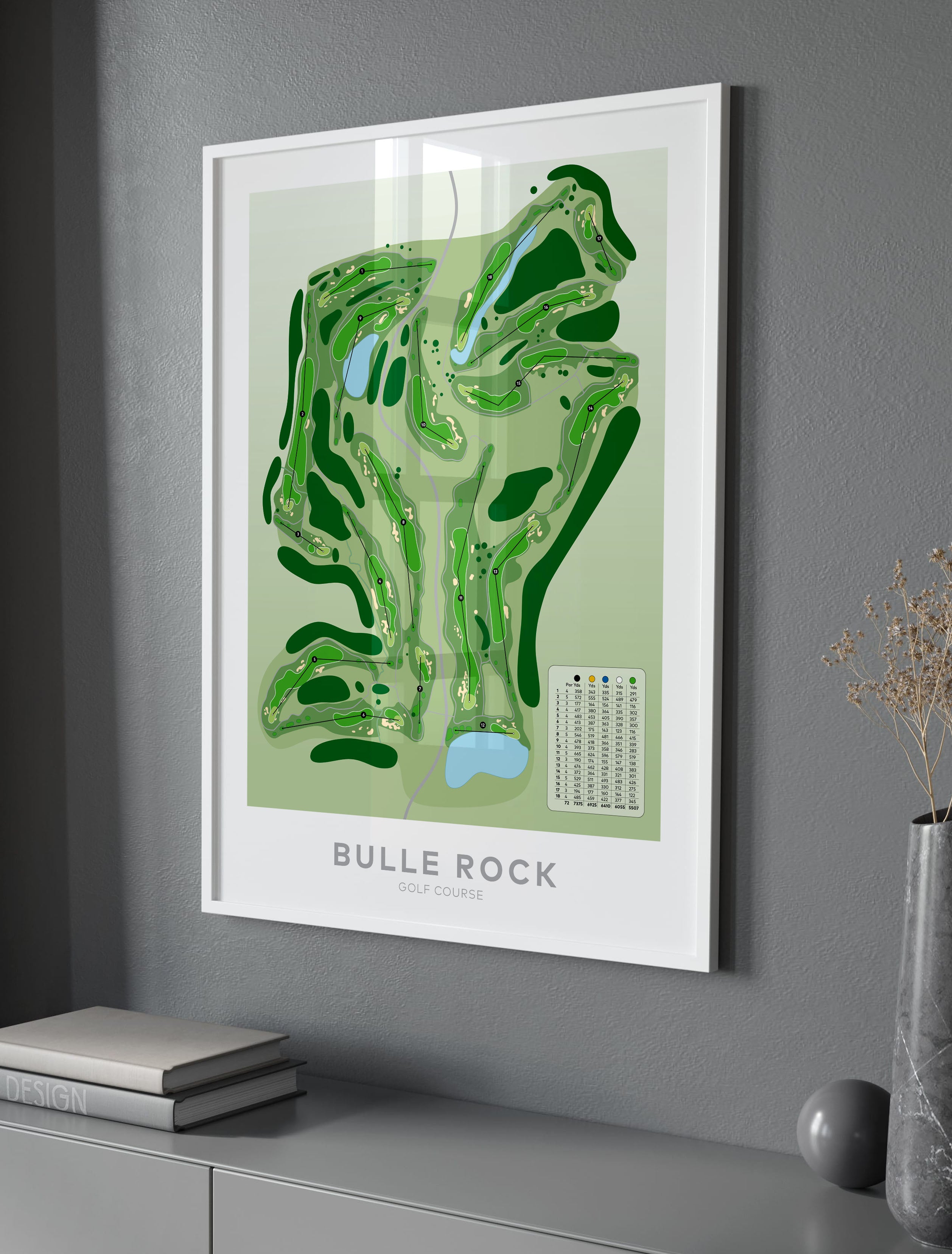 A framed golf course map print of Bulle Rock Golf Club, featuring a green and light green topographic design with a small course legend, displayed on a gray wall above a console table.